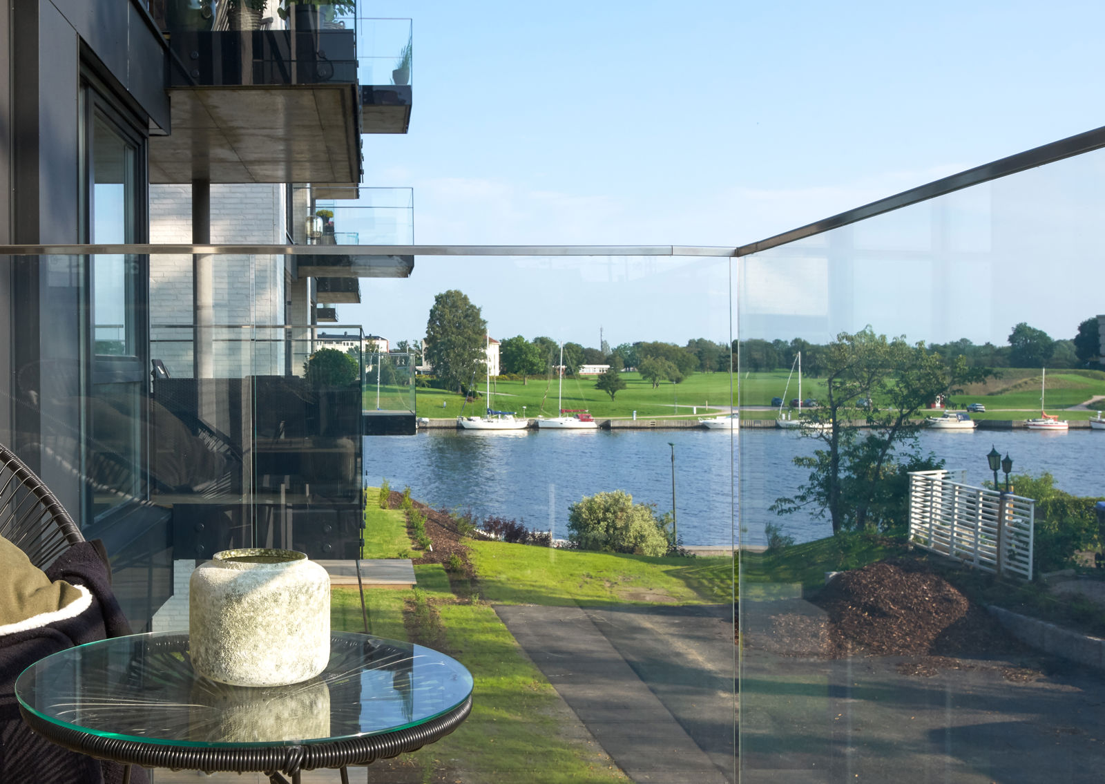 Utsikt fra innglasset terrasse mot grøntarealer og Glomma.