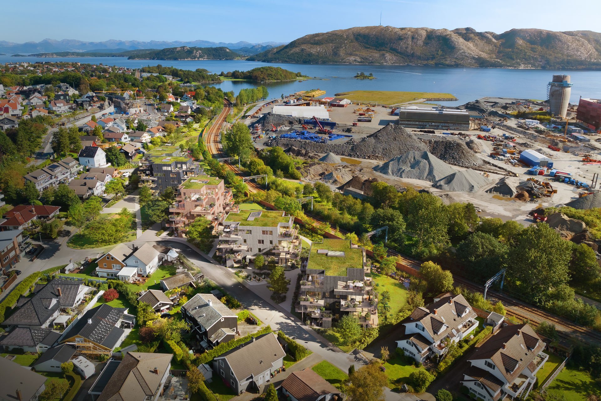 Oversiktsbilde med Drone over et boligområde med grønne omgivelser og sjøgløtt.