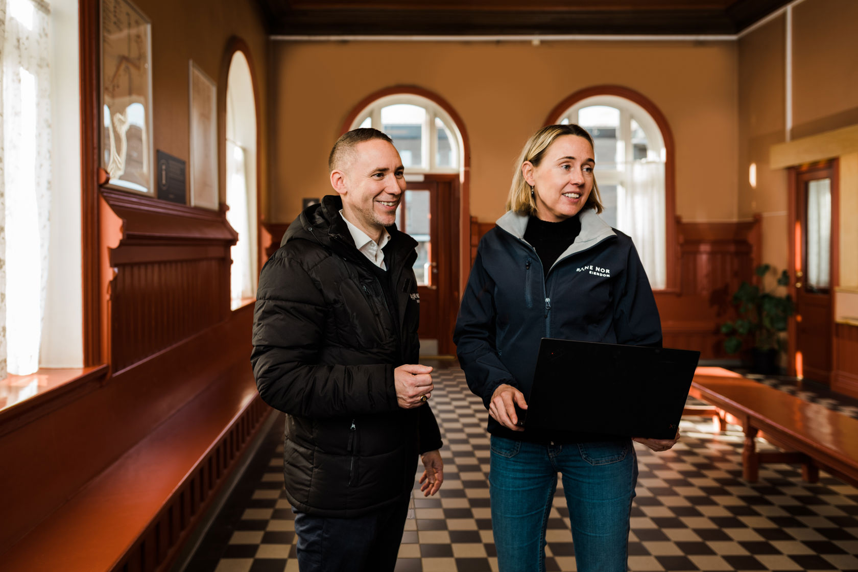 en dame og en mann er arbeidskollagaer og står sammen inne i et venterom