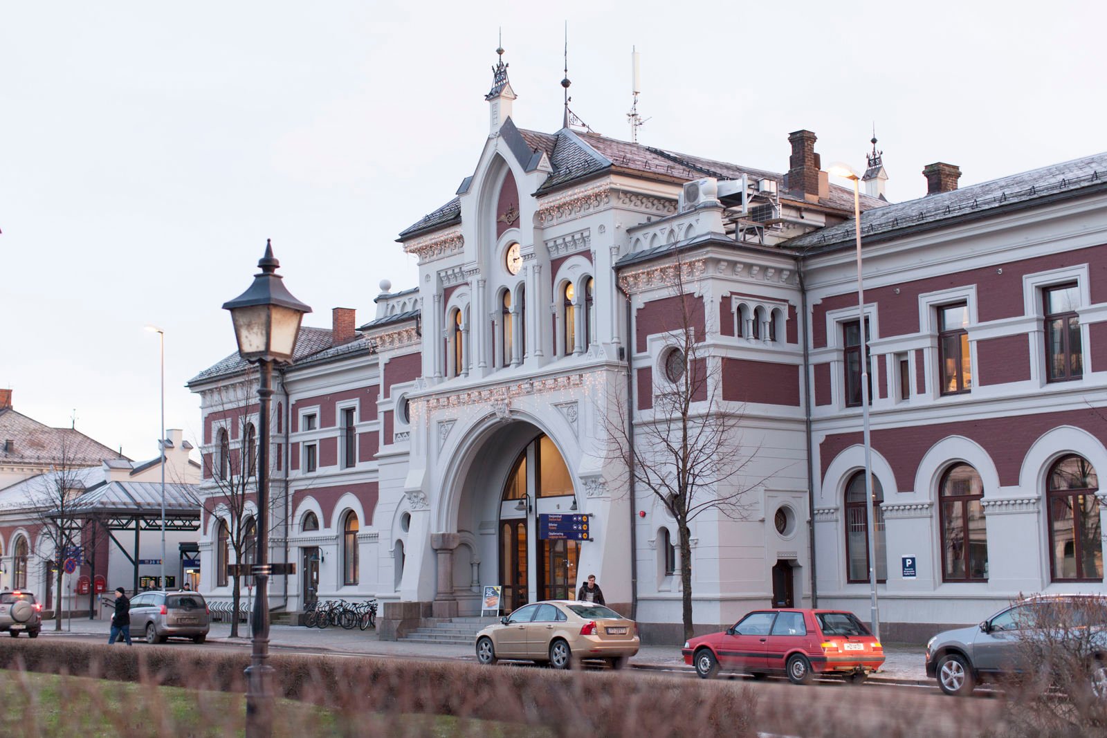 gammel jernbanestasjon i mur: Hamar stasjon i rødt og hvitt ruver foran en liten park.